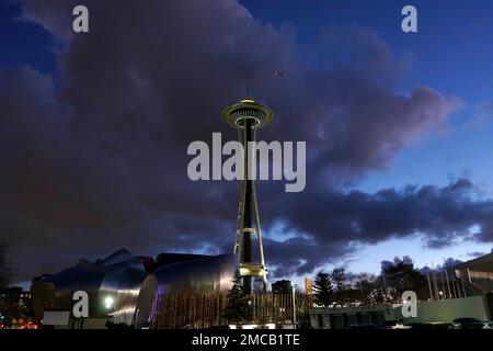 The Space Needle appears to touch a cloud as an airplane flies overhead, Monday, Jan. 31, 2022, at dusk in Seattle. (AP Photo/Ted S. Warren)
