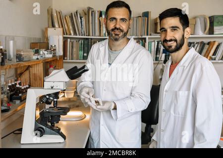 Two scientists studying dried mushroom material under the microscope in the laboratory. Teamwork. Research projects. Stock Photo