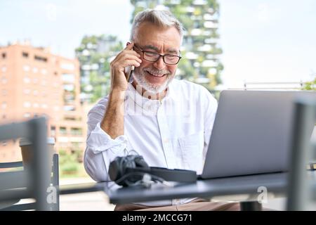 Happy older professional business man making call on mobile phone outdoors. Stock Photo