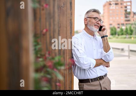 Senior older business man talking on mobile cell phone making call outdoors. Stock Photo