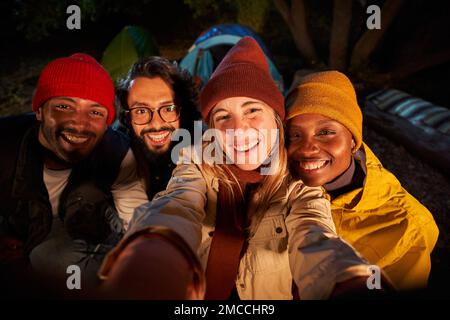 Photo of men and women smiling and taking selfie in camping forest. Stock Photo
