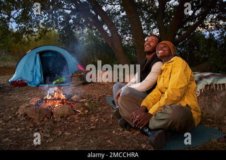 African couple spending free time and sitting during camping together on winter day. Stock Photo
