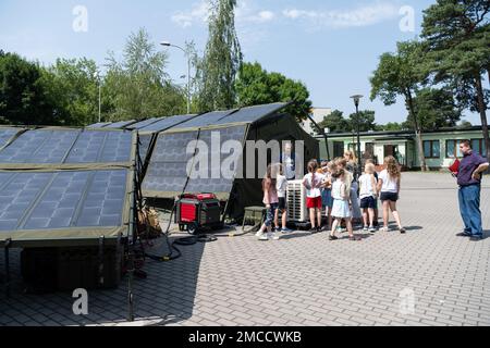 U.S. Air Force Senior Master Sgt. Brent Kenney, 52nd Civil Engineer Squadron Heavy Repair superintendent, speaks to Polish and Ukrainian children about Project Arcwater at a summer camp in Otwock, Poland, June 29, 2022. Using only sunlight and water from the air, the innovation can sustain dozens of warfighters during Agile Combat Employment, but the system is designed for a wide range of applications like humanitarian aid and disaster response. Arcwater,Energy,Humanitarian,INNOVATION,Spark Tank,solar, Stock Photo