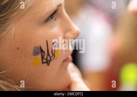 Ukrainian trident, Coat of arms of Ukraine, close-up on a cheek of an Ukrainian girl Stock Photo
