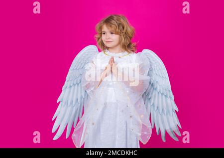 Valentines day. Little cupid angel child with wings with prayer hands, hope and pray concept. Studio portrait of angelic kid. Stock Photo