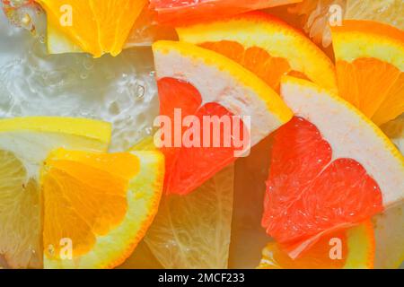 Pieces of grapefruit, orange fruit and honey pomelo in liquid with bubbles. Slices of grapefruit, orange fruit and honey pomelo in water. Fresh slices Stock Photo