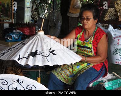 Thai craftsmanship technician drawing painting color on handmade paper umbrella for show and sale in studio workshop at Bo Sang or Borsang Umbrella vi Stock Photo