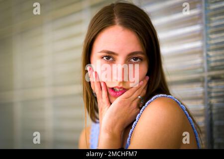 Close up Portrait of Teenage Girl Leaning Against Art Deco Glass Brick Window Stock Photo