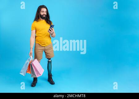 Man with prosthetic leg using the mobile holing shopping bags Stock Photo