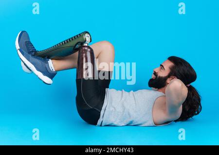 Sportive man with a prosthetic leg doing sit-ups Stock Photo