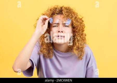 Young woman taking off her glasses to see far away Stock Photo