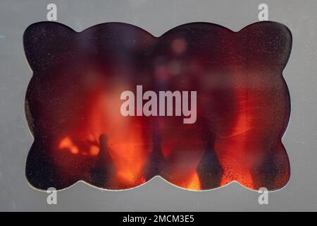 Rustic cast iron stove window where you can see the fire burning inside. Stock Photo