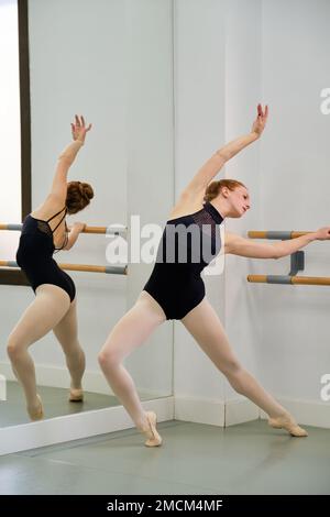 Young ballerina practicing ballet pose in a ballet school. Stock Photo