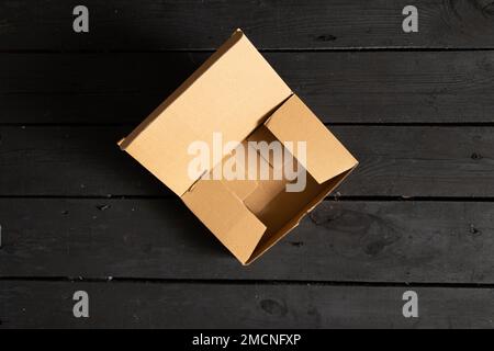 empty cardboard open box stands on black wooden floor, mail box Stock Photo