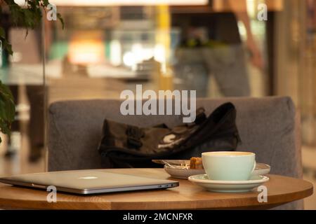 Ukraine Dnipro 15.07.2021 - Apple MacBook laptop and a cup of coffee on the table in a cafe on a break, working at a laptop in a cafe, laptop on the t Stock Photo