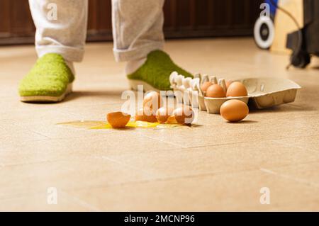 An unforeseen culinary mishap captured in a moment: eggs accidentally broken are scattered on the kitchen floor. The scene offers a glimpse into a mom Stock Photo