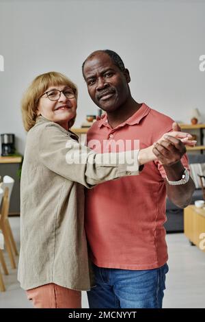 Portrait of multiethnic couple looking at camera while enjoying dance together Stock Photo