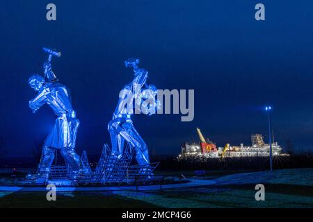 Greenock, United Kingdom. 21 January, 2023 Pictured: The Shipbuilders of Port Glasgow sculpture by John McKenna is illuminated in front of the Glen Sannox Ferry being built at the Ferguson Shipyard. Credit: Rich Dyson/Alamy Live News Stock Photo