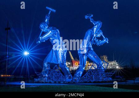 Greenock, United Kingdom. 21 January, 2023 Pictured: The Shipbuilders of Port Glasgow sculpture by John McKenna is illuminated in front of the Glen Sannox Ferry being built at the Ferguson Shipyard. Credit: Rich Dyson/Alamy Live News Stock Photo