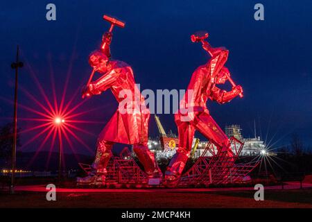 Greenock, United Kingdom. 21 January, 2023 Pictured: The Shipbuilders of Port Glasgow sculpture by John McKenna is illuminated in front of the Glen Sannox Ferry being built at the Ferguson Shipyard. Credit: Rich Dyson/Alamy Live News Stock Photo