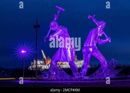 Greenock, United Kingdom. 21 January, 2023 Pictured: The Shipbuilders of Port Glasgow sculpture by John McKenna is illuminated in front of the Glen Sannox Ferry being built at the Ferguson Shipyard. Credit: Rich Dyson/Alamy Live News Stock Photo