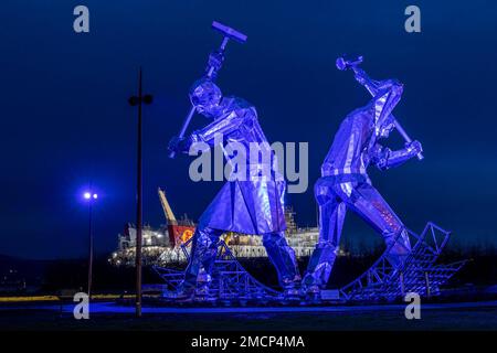 Greenock, United Kingdom. 21 January, 2023 Pictured: The Shipbuilders of Port Glasgow sculpture by John McKenna is illuminated in front of the Glen Sannox Ferry being built at the Ferguson Shipyard. Credit: Rich Dyson/Alamy Live News Stock Photo