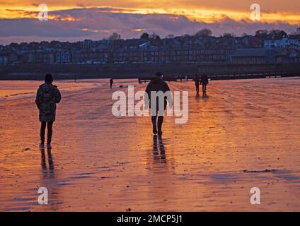 Portobello, Edinburgh, Scotland, UK. 22 January 2023. Fiery sunrise by the Firth of Forth with a slighlty milder but still nippy temperature of 5 degrees centigrade for those out and about at the seaside. Pictured: People take an early morning stroll along the shore. Credit: Scottishcreative/alamy live news. Stock Photo