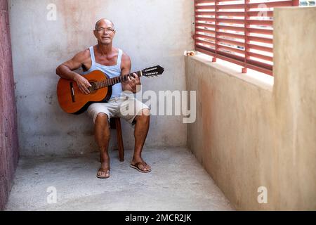 Local man playing guitar infront of his home in poor neighbourhoods of Praia town Santiago island, Cabo verde Stock Photo
