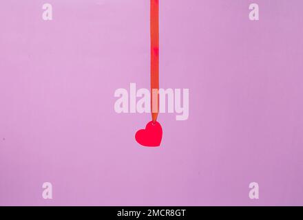Flying cleansing moisturizing hyaluronic serum acid and red paper hearts on pink background. Valentine's Day. Symbol of love. Copy space. Stock Photo