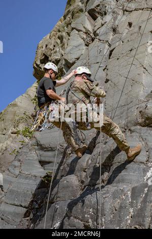 Mountaineering instructors from Northern Warfare Training Center Staff Sgts. Jordan Weeg, left, and Garrett Phillips, right, rappel down a rock face during Advanced Military Mountaineering Course 8 July at Black Rapids Training Site. The purpose of the 14-day course is to train Soldiers on how to maneuver through mountainous terrain and then go back to their units and provide the techniques and procedures to get across the mountainous terrain of Alaska. (Photo provided by Staff Sgt. Christopher Dennis/ 11th Airborne Division Public Affairs NCO) Stock Photo