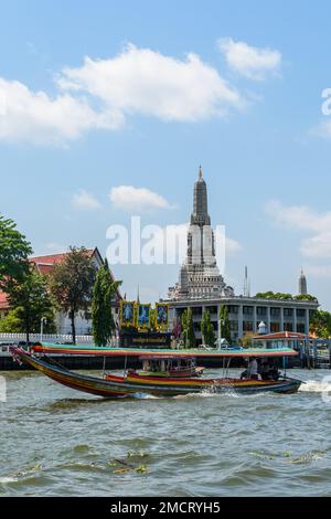 Bangkok, Thailand - March 19th 2018: A Long-tail boat on the Chao Phraya River passing the Buddhist temple Wat Arun (Temple of Dawn). Stock Photo