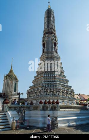 Bangkok, Thailand - March 19th 2018: A woman standing next to one of the four smaller prangs (spirals) at the Buddhist temple Wat Arun (Temple of Dawn Stock Photo