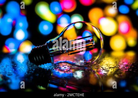 A closeup of a light bulb on the ground with vivid bokeh lights shining in the background, perfect for wallpapers Stock Photo