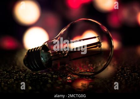 A closeup of a light bulb on the ground with vivid bokeh lights shining in the background, perfect for wallpapers Stock Photo