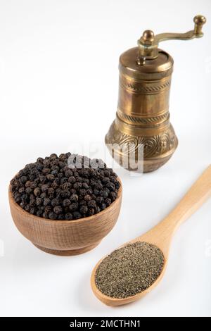 Black pepper grains, ground black pepper and metal mill on a white background Stock Photo