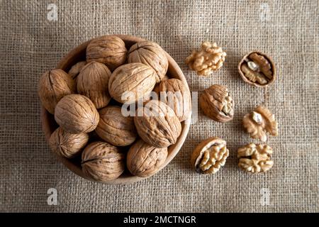 Peel walnuts and whole walnuts on burlap sack Stock Photo