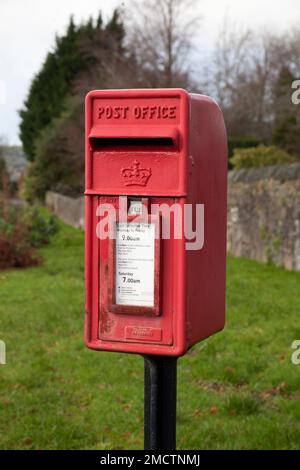 Post box on metal post, showing collection times. Stock Photo