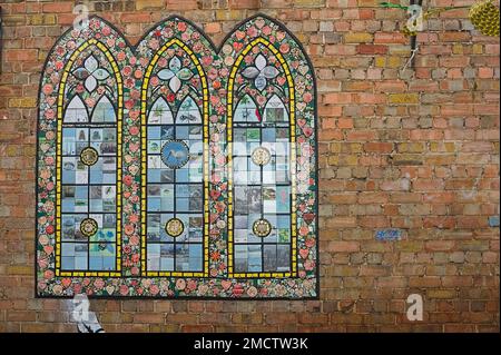 a stained glass window mosaic on a brick wall in the town Stock Photo