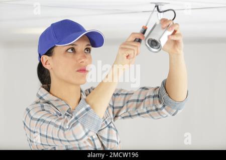 pretty female worker installing cctv camera Stock Photo