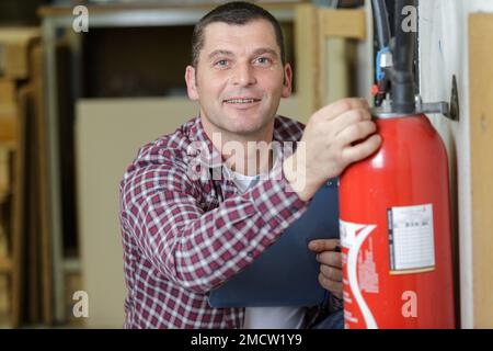 happy male professional checking a fire extinguisher Stock Photo