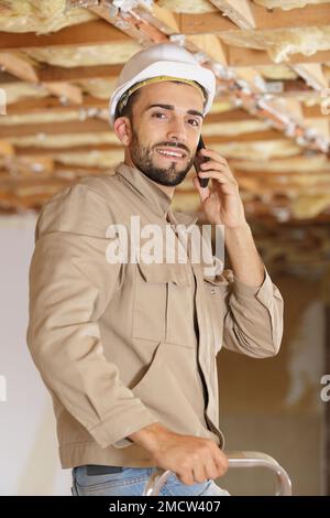 male builder stood on stepladder talking on telephone Stock Photo