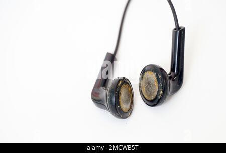 dirty and dusty used black ear buds isolated on white background. Stock Photo