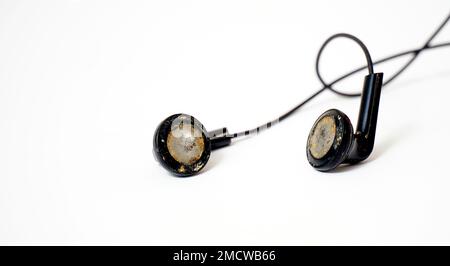 dirty and dusty used black ear buds isolated on white background. Stock Photo