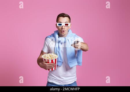 man using remote controller watching movie with big bucket of popcorns Stock Photo