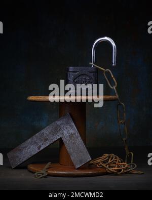 Difficulty theme, opening, still life with old padlock, rusty chain, metal bracket and wooden spool, studio shot, symbol photo Stock Photo