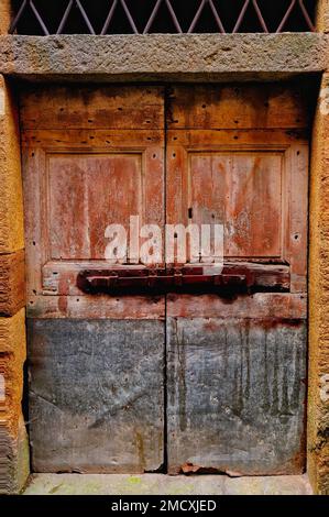 Rustic wooden door set in stone columns with large rusty bolt,  Roccatederighi Mountain village, Tuscany, Italy, Stock Photo