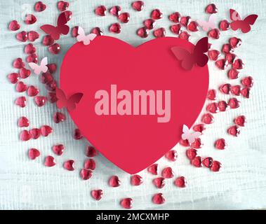 Red heart shaped gift box with red hearts and butterfly on grey background. Design for Valentine's Day. Stock Photo