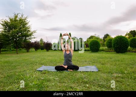 Caucasian woman, yoga instructor, doing side stretch, sitting spine side bend, seated side bend. Healthy lifestyle concept. Stock Photo