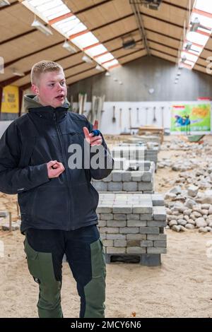 Aarhus, Denmark - November 16, 2022: Student presenting the Instruction hall of a vocational school with heaps of bricks for all kinds of practical paving instructions and training Stock Photo