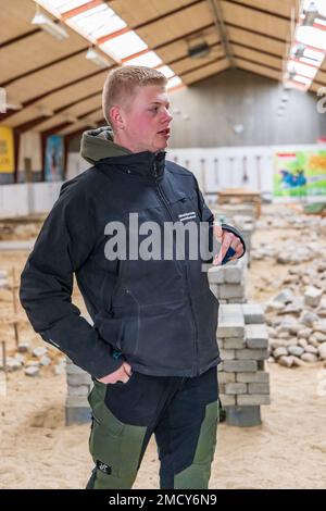 Aarhus, Denmark - November 16, 2022: Student presenting the Instruction hall of a vocational school with heaps of bricks for all kinds of practical paving instructions and training Stock Photo